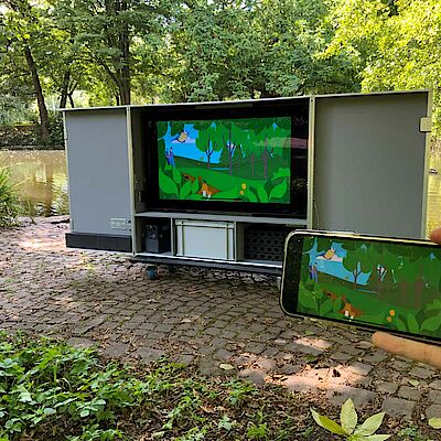 The eKami Flightcase stands in a park. This synchronizes the display of the smartphone with the TV.